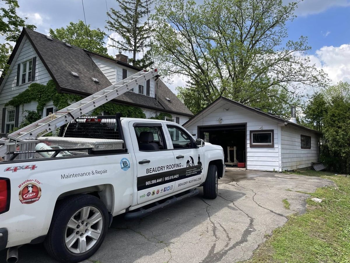Beaudry Roofing truck with ladder parked at a residential job site