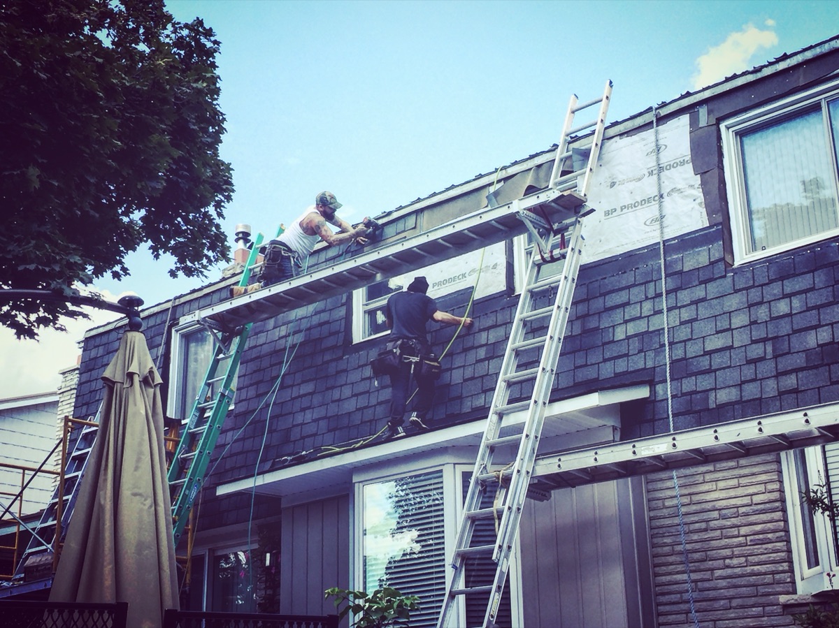 Beaudry crew on ladders working the eavestrough and roof edge of a two-storey home