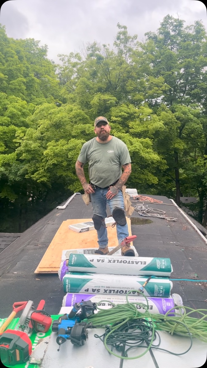 Flat roof install with rolls of self-adhered SBS membrane and a Beaudry roofer on the deck