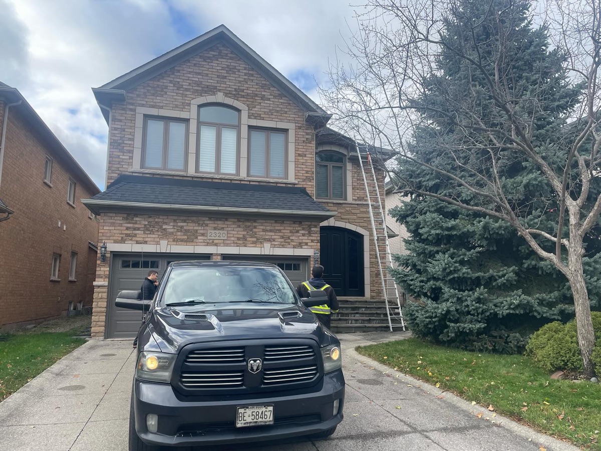 Beaudry crew and truck at a large brick two-storey home mid re-roof, ladder to the roof