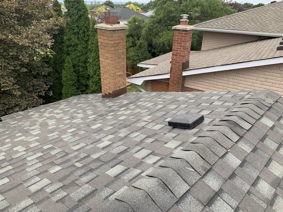 Finished shingle roof cut in neatly around two brick chimneys